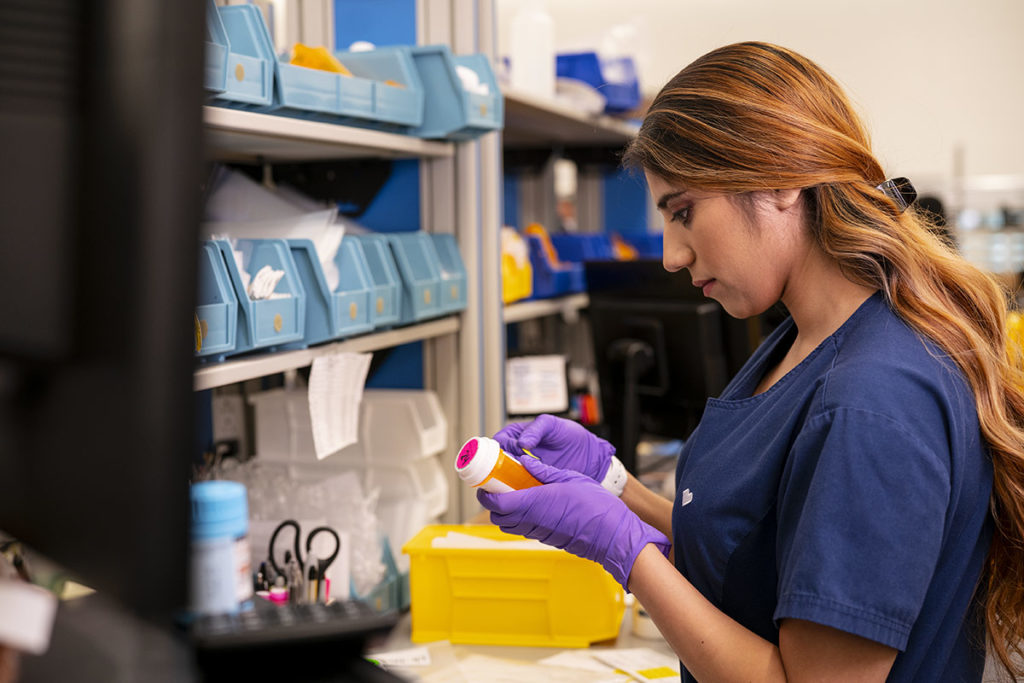 woman writing on prescription bottle